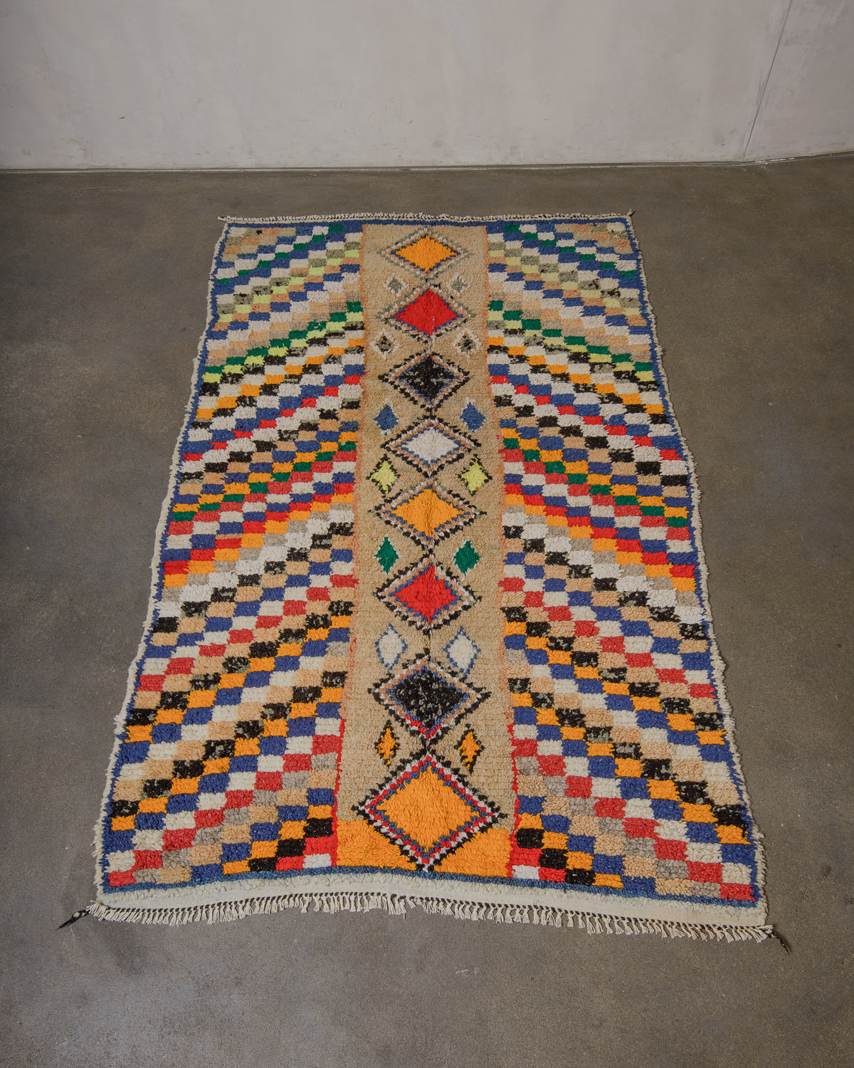 Vintage wool rug with geometric design laying on cement floor.